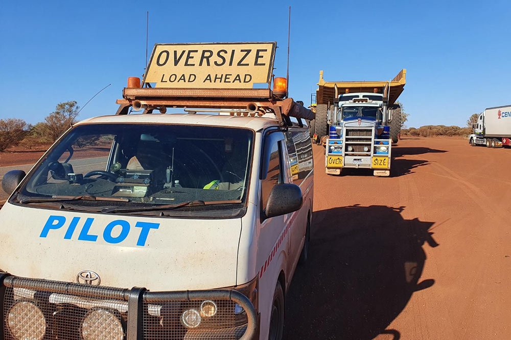 New escort pilot training with large truck carrying a huge mining dump truck
